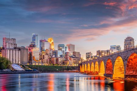 Minneapolis skyline and the Stone Arch Bridge lit at dusk